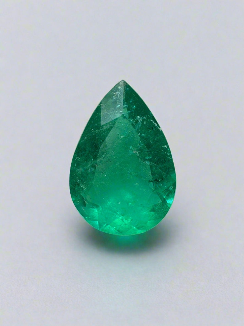 May include: A pear-shaped emerald gemstone with a deep green color. The gemstone is faceted and has a high degree of clarity.