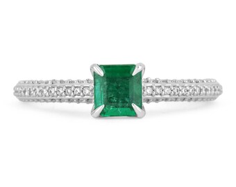 May include: A silver ring with a square emerald gemstone and a band of small diamonds.