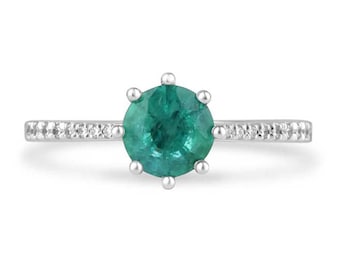 May include: A silver ring featuring a round green emerald gemstone encircled by a row of small white diamonds.