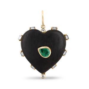 Puede incluir: Un colgante en forma de corazón negro con una piedra preciosa verde y detalles de diamantes. El colgante está hecho de madera y tiene una cadena de oro.
