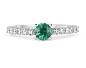 May include: A silver ring featuring a round green emerald gemstone and a band of small diamonds.