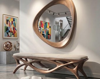 May include: A wall-mounted mirror with an irregular, organic-shaped wooden frame featuring a smooth, light brown grain. Below it sits a bench with a cream-coloured upholstered seat and a complex, branching wooden base with a matching finish.