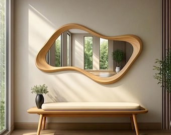 May include: A wall-mounted mirror with an irregular, organic, wavy wooden frame. The mirror reflects a room with windows and a potted plant. Below the mirror sits a wooden bench with a light-coloured cushion and a small black vase with greenery.