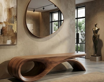 May include: A long, low-profile wooden bench featuring a continuous, fluid, curved design with a large circular cutout on one end. The bench is crafted from wood with a visible grain pattern, showcasing a smooth, polished finish throughout its structure.