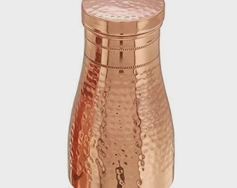 May include: A copper water bottle with a hammered texture and a matching lid. The bottle has a rounded base and tapers towards the top. The copper has a shiny, reflective surface.