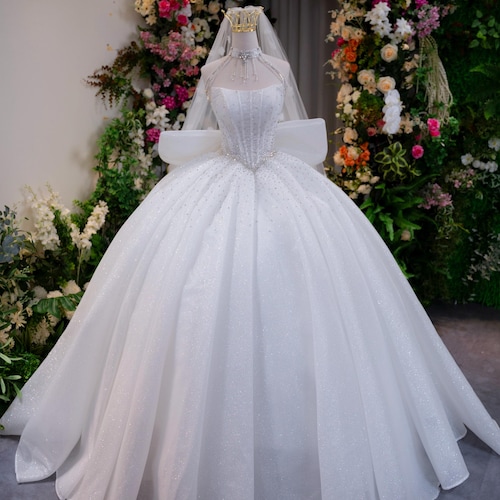 Robe de mariée blanche scintillante de style princesse, en tulle à sequins, col halter orné de perles, grand nœud dans le dos, traîne.