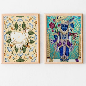 May include: Two framed art prints. The left print features a white cow and calf amidst blue lotus flowers on a yellow background. The right print depicts a blue deity with ornate gold and purple details, holding a lotus flower.