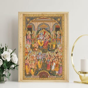May include: A framed, vibrant Hindu religious artwork showing a royal court scene. The artwork features many figures in traditional dress, with a central couple seated on a throne. The frame is a light wood colour, and the overall style is detailed and ornate.