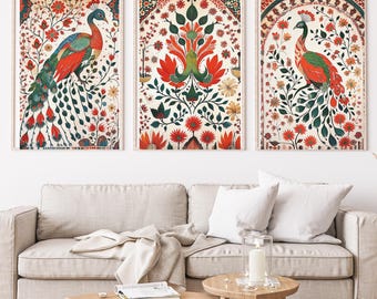 May include: Three framed art prints featuring peacock illustrations. The artwork showcases vibrant peacocks with red, green, and blue plumage, set against a backdrop of floral patterns in red, green, and cream. The prints are displayed above a beige sofa.