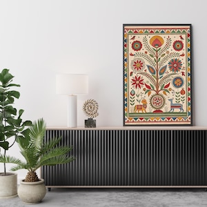 May include: A framed art print featuring a colorful tree of life design. The artwork includes red, yellow, and blue floral elements, birds, and animal figures. The print is displayed on a black cabinet with a white lamp and decorative sculpture.