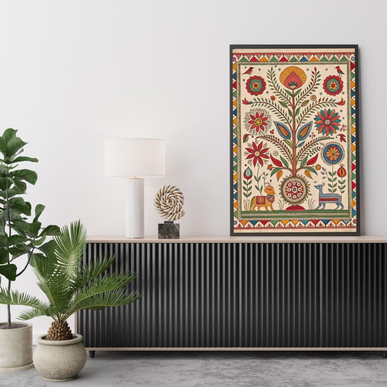 May include: A framed art print featuring a colorful tree of life design. The artwork includes red, yellow, and blue floral elements, birds, and animal figures. The print is displayed on a black cabinet with a white lamp and decorative sculpture.