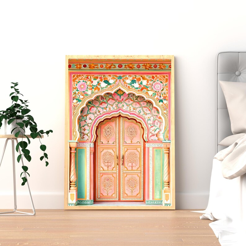 May include: A framed print depicting a detailed illustration of a traditional Indian door. The door is painted in shades of pink, peach, and green, with intricate floral and tree designs. The artwork is set against a white background, with a wooden frame.