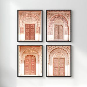 May include: Four framed prints featuring architectural details of ornate archways and doors. The prints showcase a warm color palette of reds, pinks, and creams. Each print is encased in a black frame, creating a cohesive set.