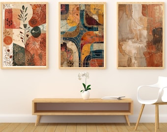 May include: Three framed abstract art prints with warm color palettes. The prints feature geometric shapes, botanical elements, and textured backgrounds in shades of orange, brown, and blue. The frames are a light wood color.