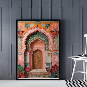 May include: A framed art print of an Indian palace entrance. The artwork shows a detailed archway with intricate floral patterns in pink, orange, green, and gold. The wooden door is a central feature.