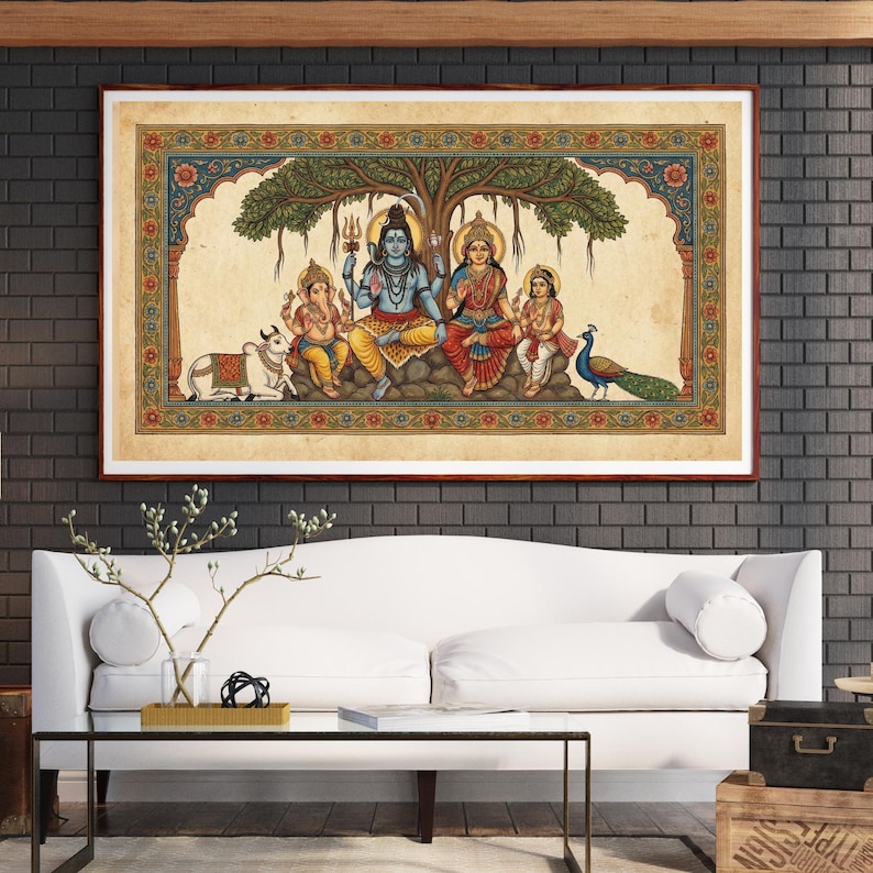 Puede incluir: Pintura enmarcada y colorida que representa a una familia hind&uacute; bajo un &aacute;rbol. La obra presenta figuras con vestimenta tradicional, una vaca y un pavo real. El marco es marr&oacute;n y la pintura se exhibe sobre un sof&aacute; blanco.