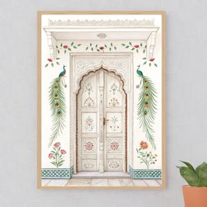 May include: Watercolor print of a white arched doorway with intricate carvings and floral details. Two peacocks with long, colorful tail feathers flank the door. Red and pink flowers and green vines decorate the wall. The artwork is framed in a light wood.