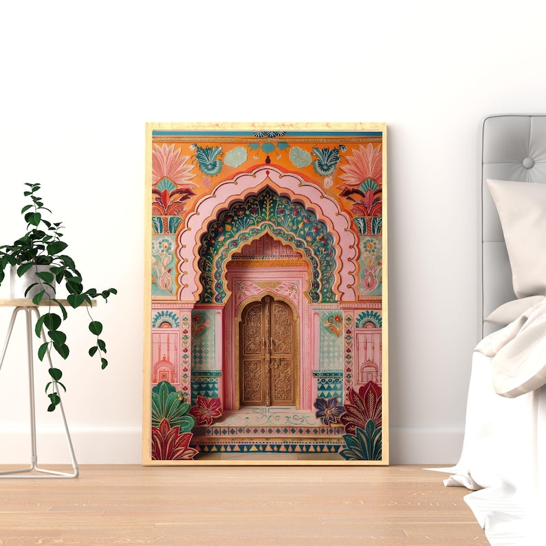 May include: A framed print depicting an elaborately decorated archway and door, with floral and geometric patterns. The artwork uses pink, orange, green, and gold, suggesting a rich cultural heritage and architectural detail. The print is displayed on a white wall.