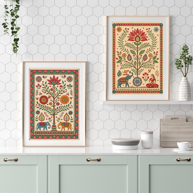May include: Two framed art prints with a beige background and colorful floral and elephant designs. The prints have a gold frame and are displayed on a white countertop. The art features a tree with a large flower at the top and elephants at the base.
