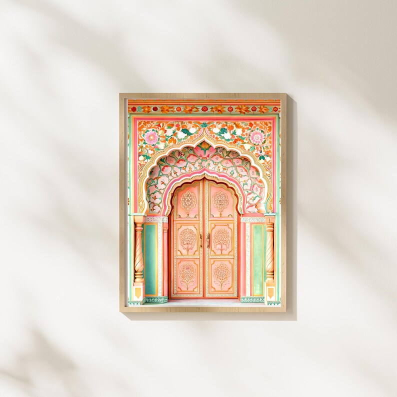 May include: A framed print depicting a detailed illustration of an ornate, arched doorway. The door is painted in shades of pink and peach, with intricate floral and tree designs. The frame is a light wood colour, set against a white background.