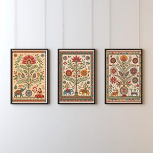 May include: Three framed art prints with colorful, detailed illustrations of trees, elephants, and floral patterns. The artwork features a cream-colored background with red, blue, yellow, and green accents. Each print is in a black frame.