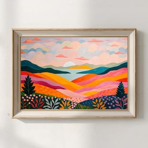 May include: A framed landscape painting with a vibrant colour palette. The artwork depicts rolling hills in shades of orange, pink, and purple, with a body of water and a sunset in the background. The sky is filled with pastel clouds, and the frame is a light beige.