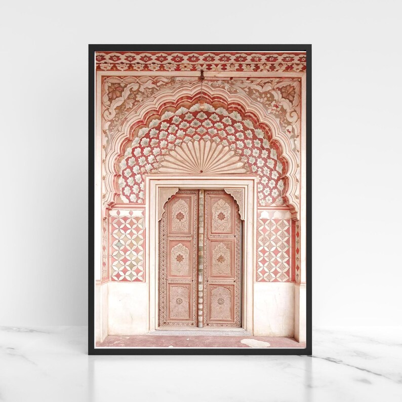 May include: Framed print featuring an ornate archway and double doors. The arch is decorated with red and white floral patterns. The doors are a light pink color with intricate carvings. The frame is black, and the background is white.