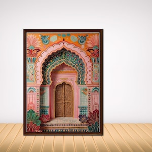 May include: A framed print depicting an ornate Indian palace entrance. The artwork showcases a detailed archway and door in shades of pink, green, and gold, with floral and geometric patterns. The frame is a dark brown colour.