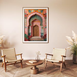 May include: A framed art print depicting a vibrant illustration of an ornate archway and door. The artwork features intricate details in pink, teal, orange, and gold. The print is displayed in a room with wooden chairs and a round coffee table.