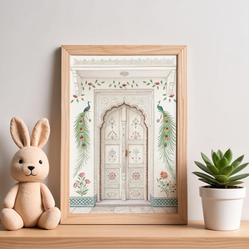 May include: A framed print of a white ornate door with floral and peacock accents. The artwork is in a light wood frame and is displayed on a wooden surface. A plush bunny and a potted succulent are next to the framed print.
