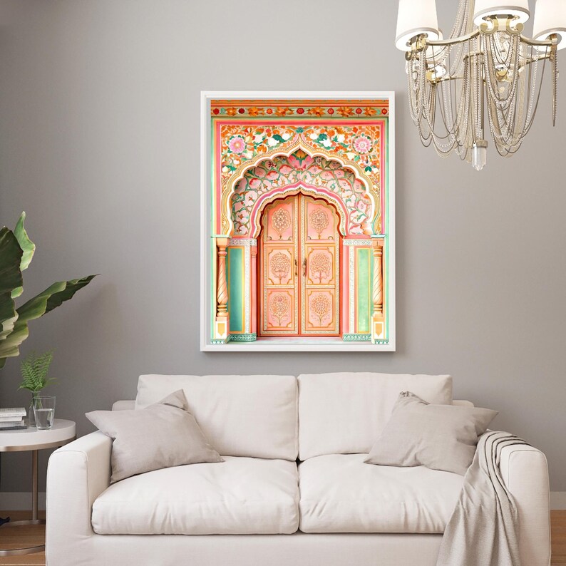 May include: A framed print of an ornate, peach-coloured door with intricate floral and tree designs. The archway and door frame feature a vibrant mix of pink, orange, green, and gold. The artwork is displayed above a white sofa.