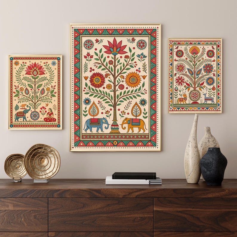 May include: Three framed art prints with gold frames, featuring colorful Indian folk art. The artwork depicts stylized trees, elephants, and floral patterns in red, blue, yellow, and green against a cream background. The prints are displayed above a dark wood cabinet.