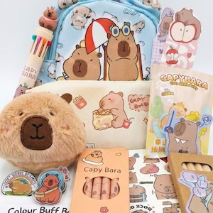 May include: A collection of capybara-themed stationery and accessories. Includes a light blue backpack, pencil case, plush toy, stickers, and a box of colored pencils. The items feature capybara illustrations and the text "CAPY BARA".