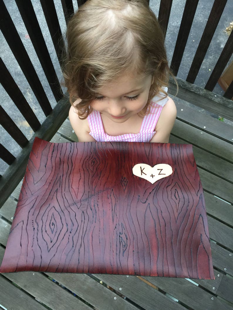 May include: A brown leather placemat with a wood grain pattern. A small white heart with the text "K+Z" is in the center of the placemat.