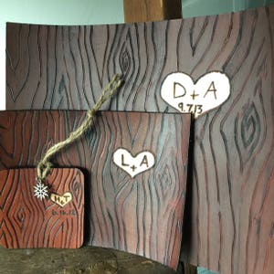 May include: Three wooden plaques with a wood grain pattern and heart-shaped designs. The top plaque has the initials "D+A" and the date "9.7.13". The middle plaque has the initials "L+A" and the bottom plaque has the initials "H+T" and the date "6.16.12".