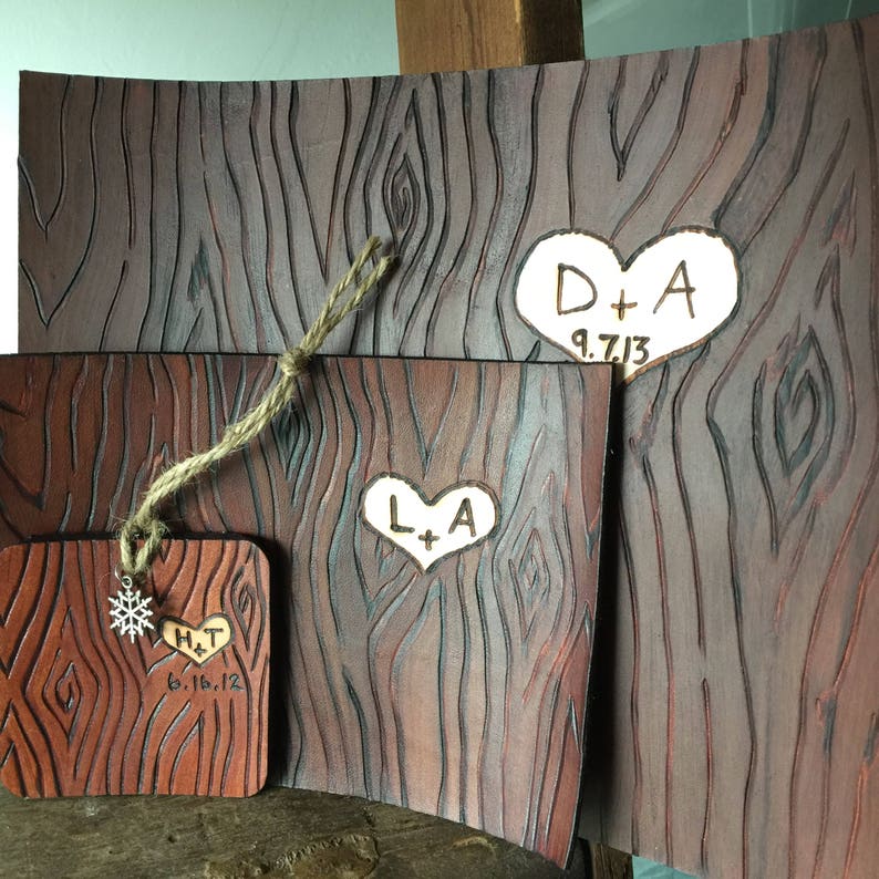 May include: Three wooden plaques with a wood grain pattern and heart-shaped designs. The top plaque has the initials "D+A" and the date "9.7.13". The middle plaque has the initials "L+A" and the bottom plaque has the initials "H+T" and the date "6.16.12".