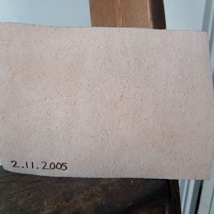 May include: A close-up of a light beige piece of leather with a date stamped on it, "2.11.2005".
