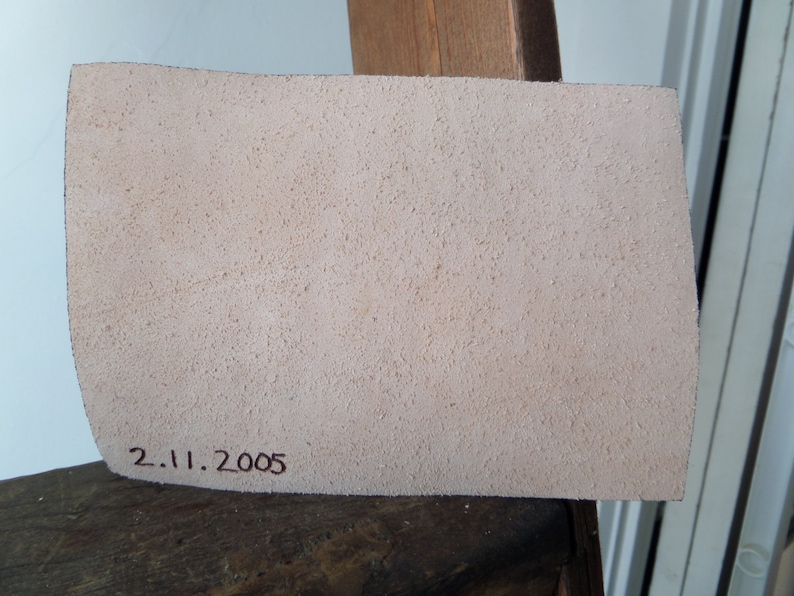 May include: A close-up of a light beige piece of leather with a date stamped on it, "2.11.2005".