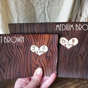 May include: Two leather samples in light brown and medium brown with a wood grain texture. The samples are engraved with hearts and initials, "J + C 4.3.2012" and "D + B 3.17.12".