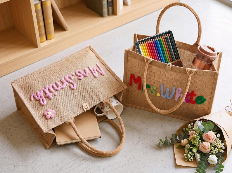May include: Two rectangular tan jute tote bags with rope handles and button closures. One bag features the pink embroidered text Mrs. Smith and a small pink flower. The other bag displays the multicolored embroidered text Mrs. White.