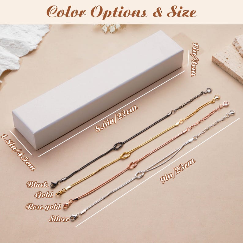 K&ouml;nnte beinhalten: Draufsicht auf eine wei&szlig;e rechteckige Schachtel und vier filigrane Kettenarmb&auml;nder in Schwarz, Gold, Ros&eacute;gold und Silber. Die Armb&auml;nder sind ca. 23 cm lang. Der Text "Color Options & Size" befindet sich oben.