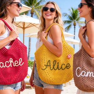 May include: Three women holding crochet tote bags. The bags are in red, yellow, and brown. Each bag has a name embroidered on it: Rachel, Alice, and Camila. The bags have a flower attached to them.