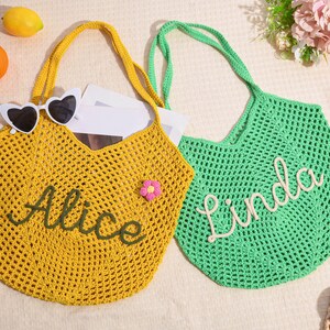 May include: Two crochet tote bags, one yellow and one green, with long handles. The yellow bag has the name "Alice" embroidered in green, and the green bag has the name "Linda" embroidered in white. Heart-shaped sunglasses rest on the yellow bag.