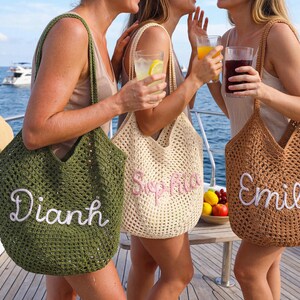 May include: Three open-weave tote bags in green, beige, and brown, each with a name embroidered in a contrasting color. The bags are held by people on a boat, with drinks and a hat visible. The names are Dianh, Sophia, and Emily.