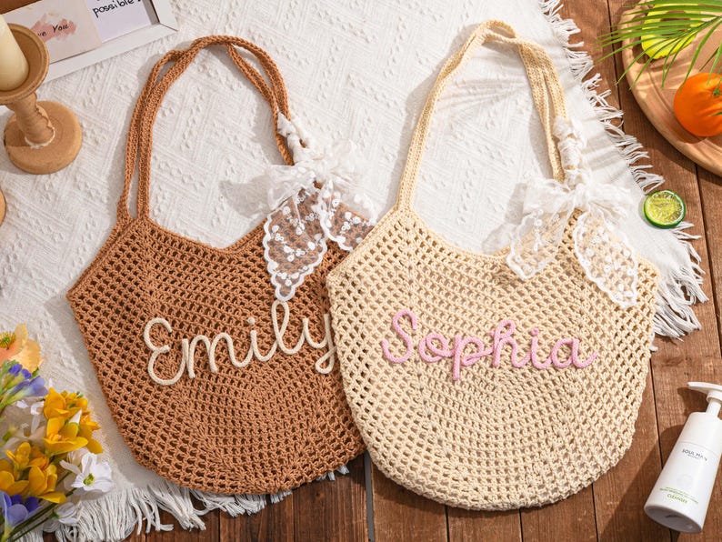 May include: Two crochet tote bags, one brown and one beige, with long handles and decorative lace bows. The brown bag has the name "Emily" stitched on it, and the beige bag has the name "Sophia" stitched on it.