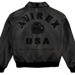 May include: Black leather jacket with the word "AVIREX" arched across the upper back, above a circular emblem and the word "USA". The jacket has a ribbed black hem and cuffs.