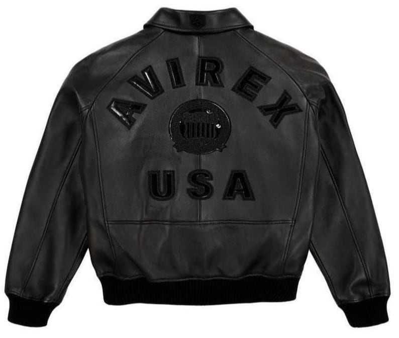 May include: Black leather jacket with the word "AVIREX" arched across the upper back, above a circular emblem and the word "USA". The jacket has a ribbed black hem and cuffs.