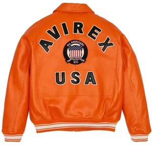 May include: A bright orange varsity jacket featuring the black text AVIREX arched across the upper back. Below the text is a circular patch with a flag graphic and the words ALL AMERICANS ESTABLISHED 1975. The word USA is printed in large black letters.