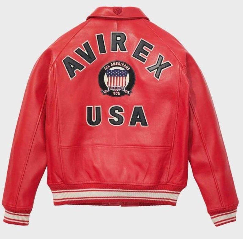 May include: A red leather jacket featuring the word "AVIREX" across the shoulders. Below is a circular patch with "ALL AMERICANS" and "ESTABLISHED 1975". The word "USA" is below the patch. The jacket has a white and red striped trim at the waist and cuffs.