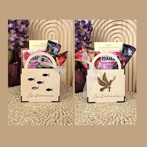 May include: Two wooden gift boxes, one with fish cutouts and the text "Zur Kommunion", the other with a dove and cross design and the text "Zur Konfirmation". Both boxes are filled with various treats and tied with a white ribbon.